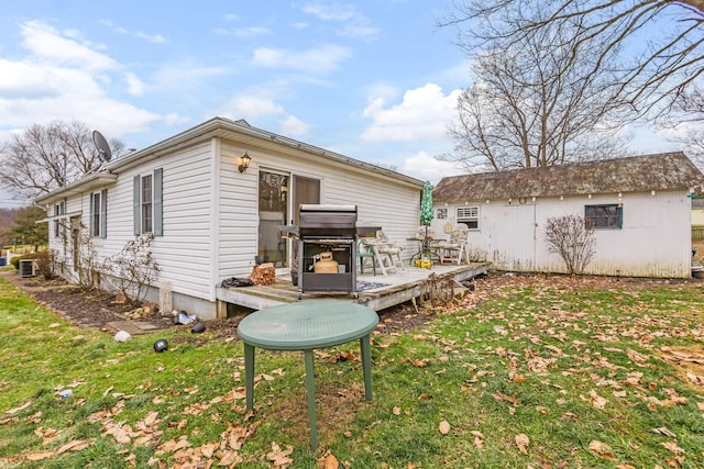 rear view of property with a wooden deck, a yard, and an outdoor structure