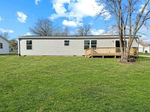 rear view of property featuring a wooden deck and a yard