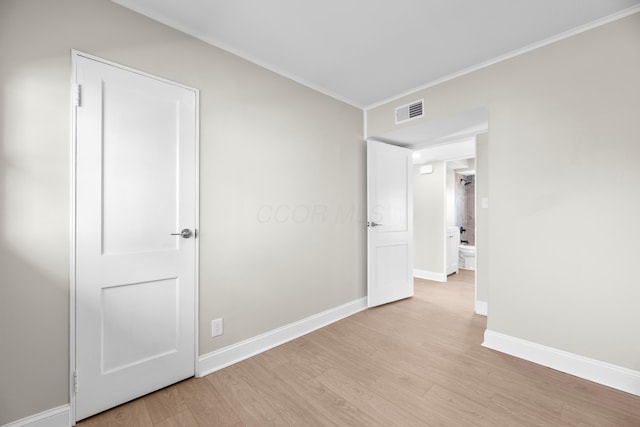 empty room featuring light wood-type flooring and crown molding