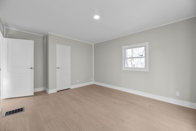 spare room with ornamental molding and light hardwood / wood-style flooring