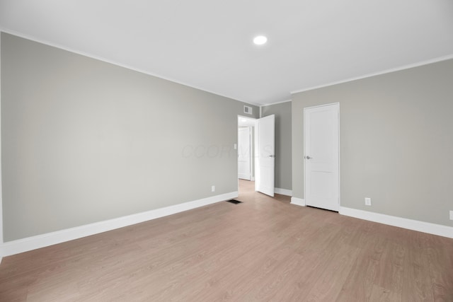 spare room with light wood-type flooring and crown molding