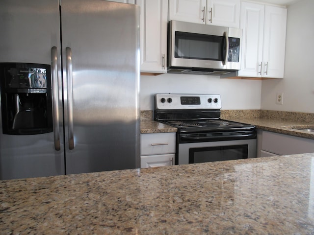 kitchen with stone counters, white cabinetry, and stainless steel appliances