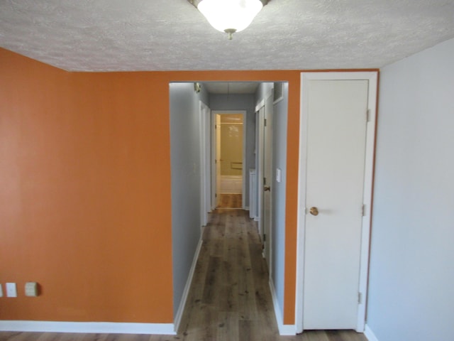 hall with wood-type flooring and a textured ceiling