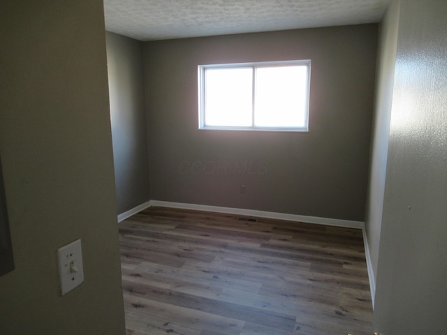 empty room featuring light hardwood / wood-style floors and a textured ceiling