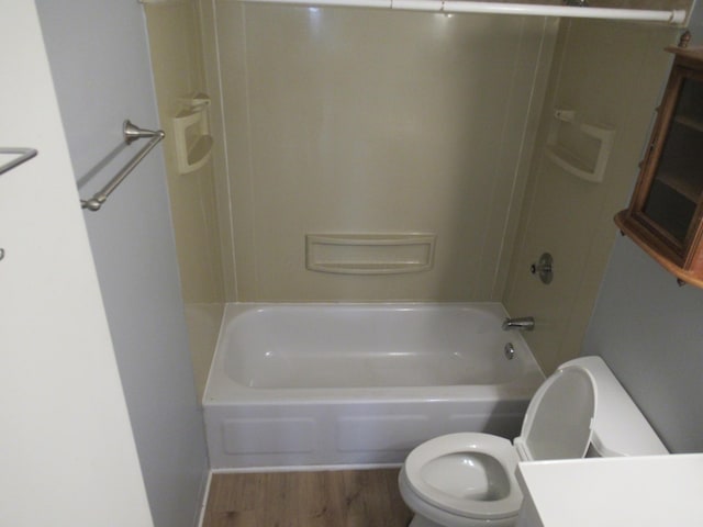 bathroom with washtub / shower combination, hardwood / wood-style floors, and toilet