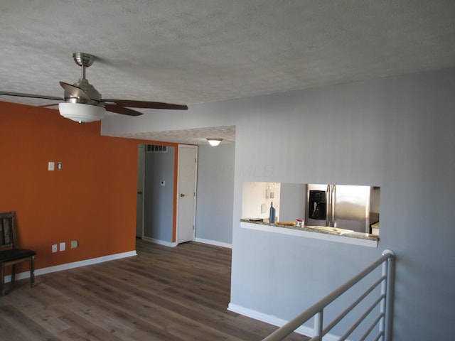 unfurnished living room featuring a textured ceiling, ceiling fan, and dark wood-type flooring