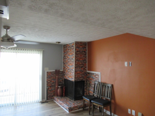 living room featuring ceiling fan, a healthy amount of sunlight, a multi sided fireplace, and light hardwood / wood-style flooring