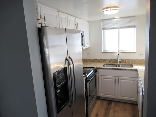 kitchen with dark wood-type flooring, white cabinets, sink, light stone countertops, and stainless steel appliances