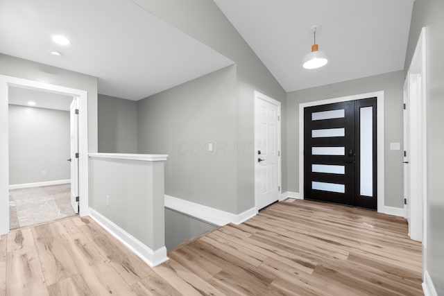 foyer entrance with vaulted ceiling and light hardwood / wood-style flooring