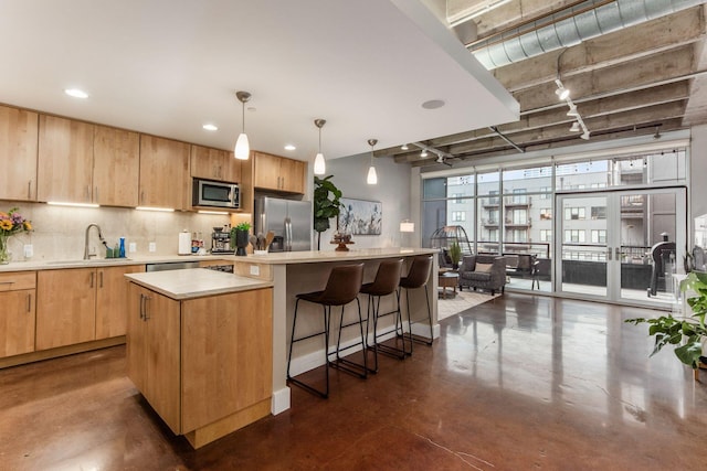 kitchen with a center island, sink, hanging light fixtures, a breakfast bar area, and stainless steel appliances