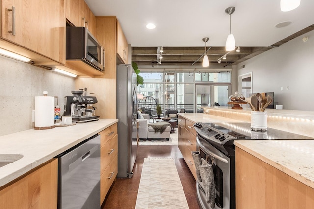 kitchen featuring light stone countertops, rail lighting, tasteful backsplash, stainless steel appliances, and hanging light fixtures