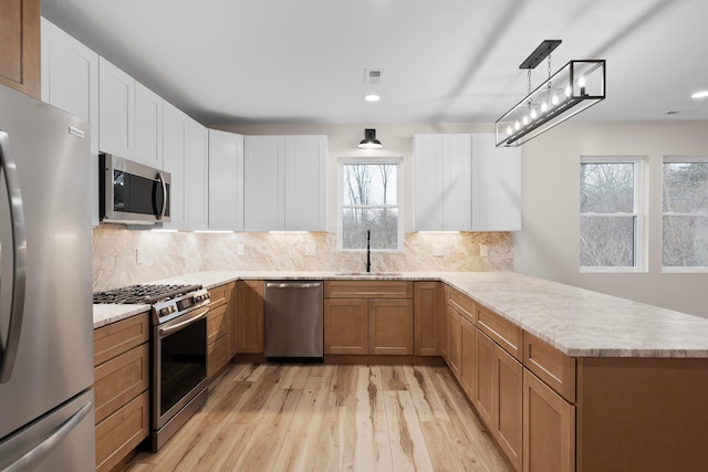 kitchen with white cabinetry, kitchen peninsula, sink, and appliances with stainless steel finishes