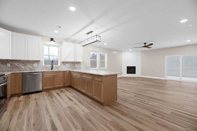 kitchen featuring pendant lighting, ceiling fan, light wood-type flooring, a fireplace, and appliances with stainless steel finishes