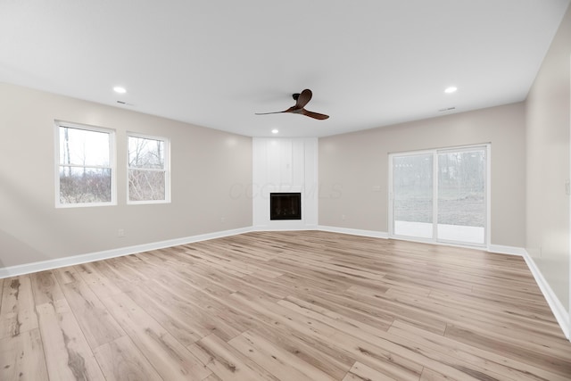 unfurnished living room with a wealth of natural light, ceiling fan, a fireplace, and light hardwood / wood-style flooring