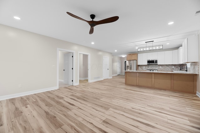 unfurnished living room with ceiling fan, light hardwood / wood-style floors, and sink