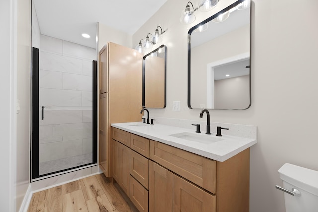 bathroom featuring wood-type flooring, vanity, toilet, and walk in shower