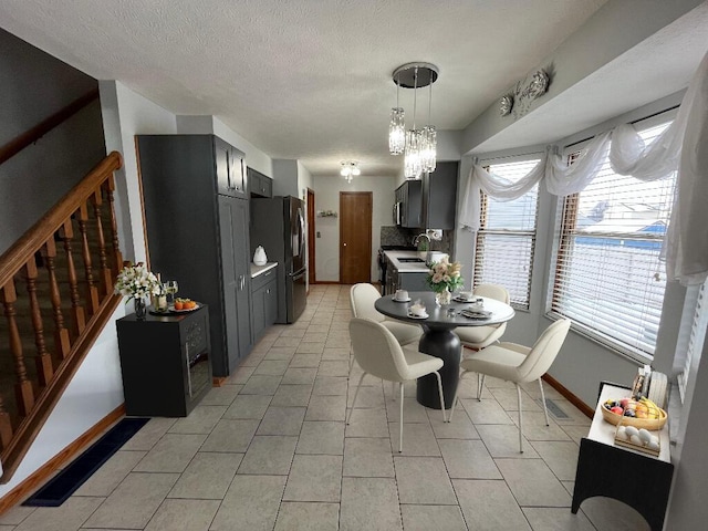 dining area featuring sink, light tile patterned floors, and a textured ceiling