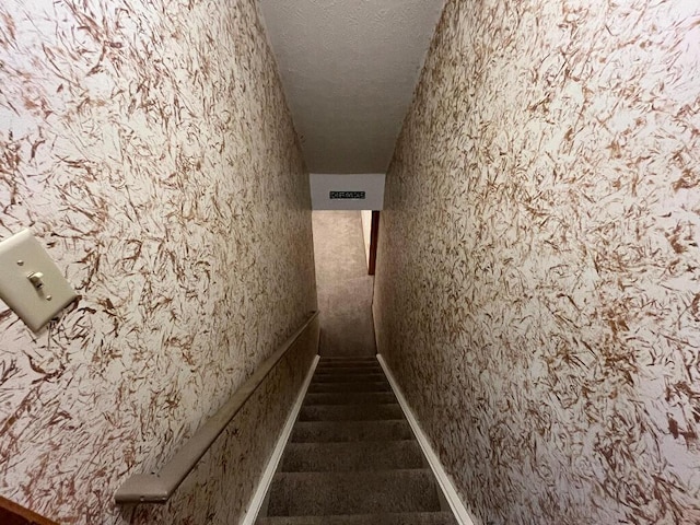 stairway featuring a textured ceiling