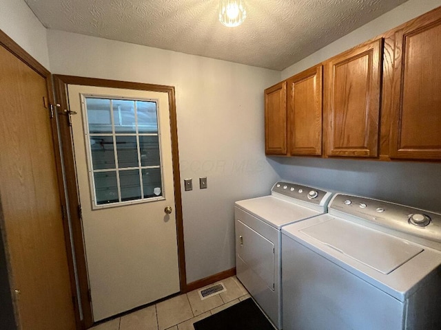 clothes washing area with cabinets, independent washer and dryer, a textured ceiling, and light tile patterned floors