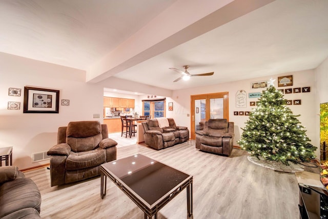 living room featuring ceiling fan, beam ceiling, and light hardwood / wood-style floors