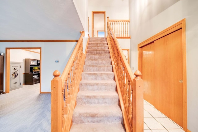 stairs featuring wood-type flooring and ornamental molding