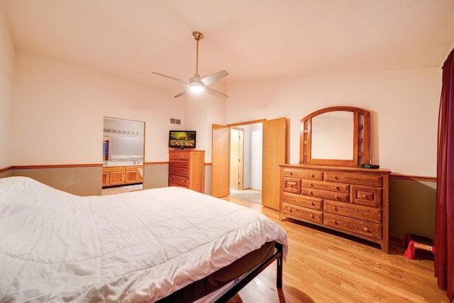 bedroom featuring ceiling fan, lofted ceiling, connected bathroom, and light wood-type flooring