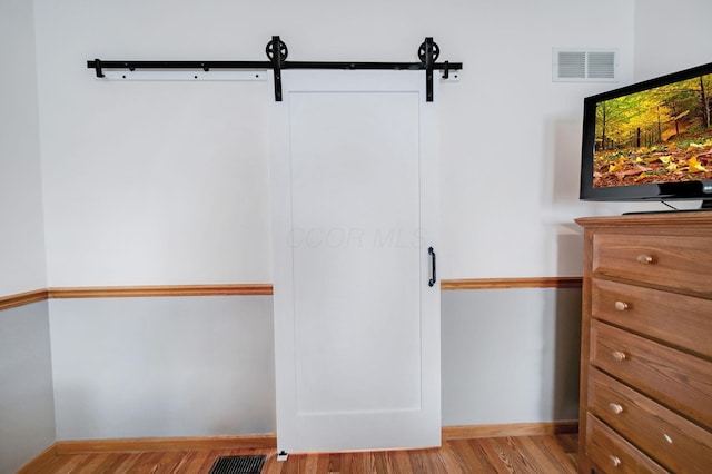 walk in closet featuring a barn door and light wood-type flooring