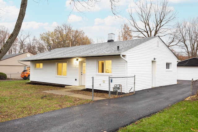 rear view of property featuring a garage, an outdoor structure, and a yard