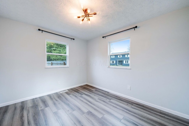 unfurnished room with plenty of natural light, a textured ceiling, and light wood-type flooring