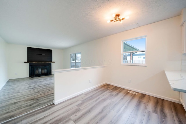 unfurnished living room featuring a textured ceiling and light wood-type flooring