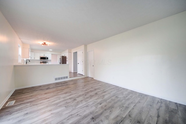 unfurnished living room with sink and light hardwood / wood-style flooring