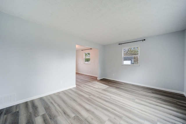 unfurnished room with light hardwood / wood-style flooring and a textured ceiling