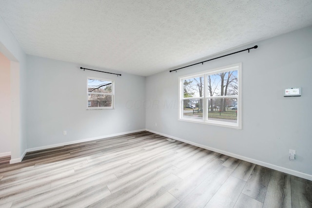 spare room with a textured ceiling and light wood-type flooring