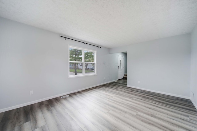 spare room with a textured ceiling and light wood-type flooring