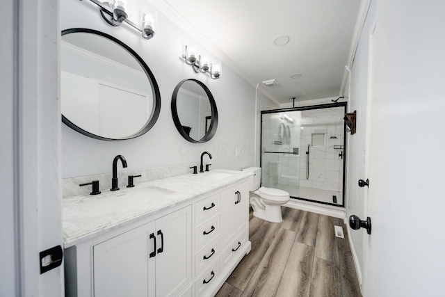 bathroom with walk in shower, wood-type flooring, toilet, vanity, and ornamental molding