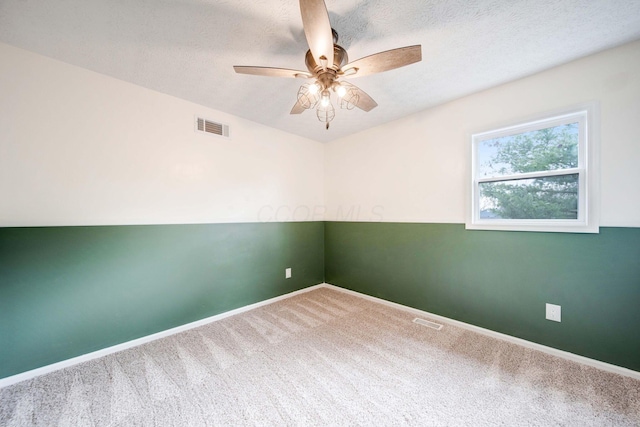 carpeted spare room featuring ceiling fan and a textured ceiling