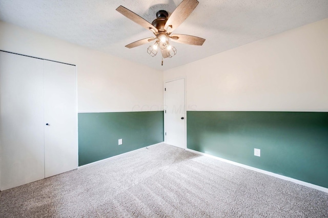 unfurnished bedroom featuring a textured ceiling, carpet floors, a closet, and ceiling fan