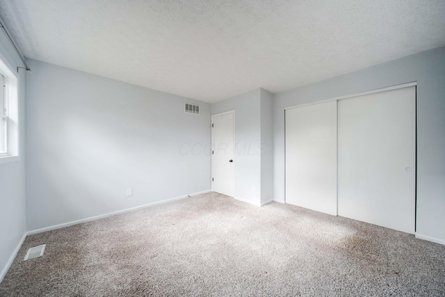 unfurnished bedroom with a textured ceiling, carpet floors, and a closet