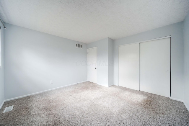 unfurnished bedroom with carpet, a textured ceiling, and a closet