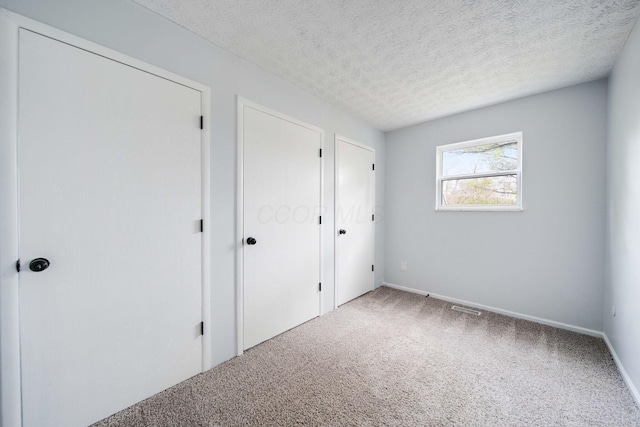 unfurnished bedroom with a textured ceiling and carpet floors