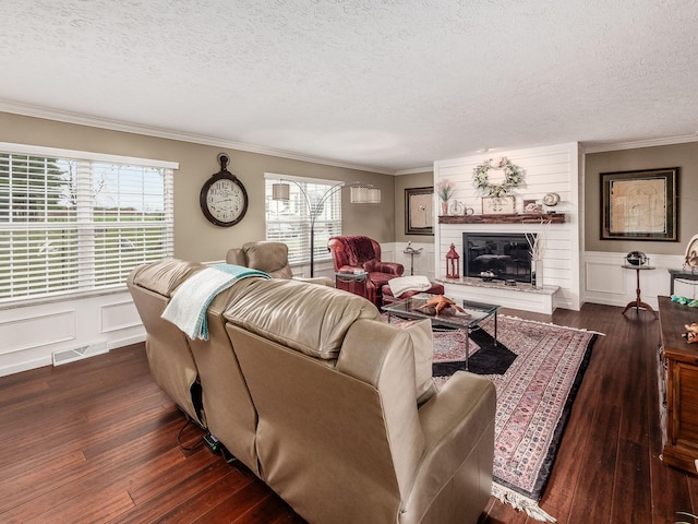 living room featuring dark hardwood / wood-style floors, ornamental molding, a textured ceiling, and a brick fireplace