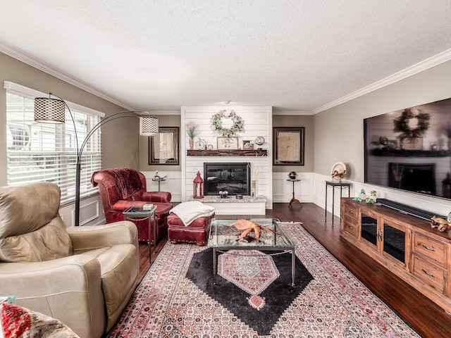 living room with a large fireplace, hardwood / wood-style floors, a textured ceiling, and ornamental molding