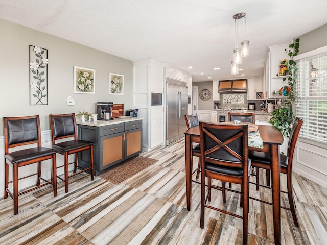 kitchen featuring backsplash, decorative light fixtures, wall chimney exhaust hood, gray cabinets, and premium appliances