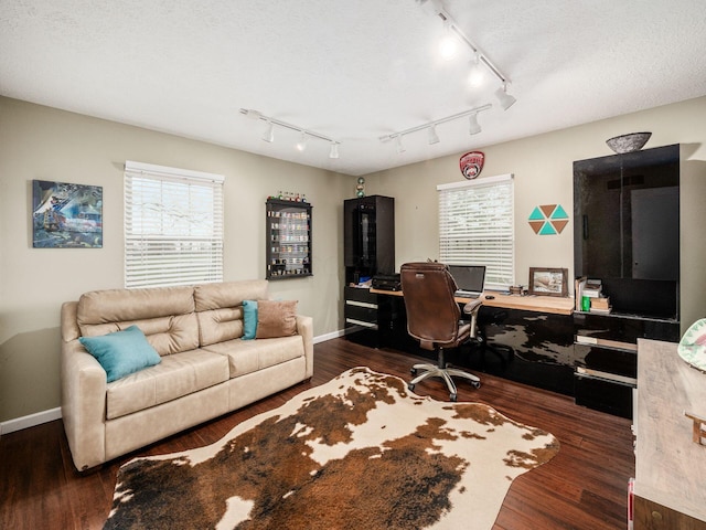 office space featuring a wealth of natural light, rail lighting, dark wood-type flooring, and a textured ceiling