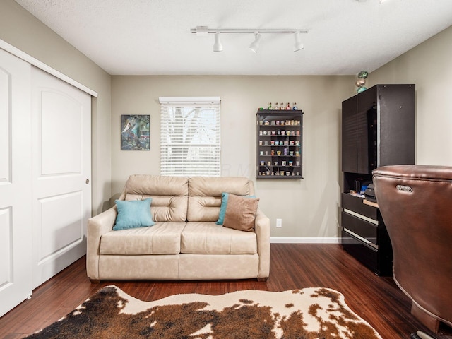 living room with a textured ceiling, track lighting, and dark wood-type flooring