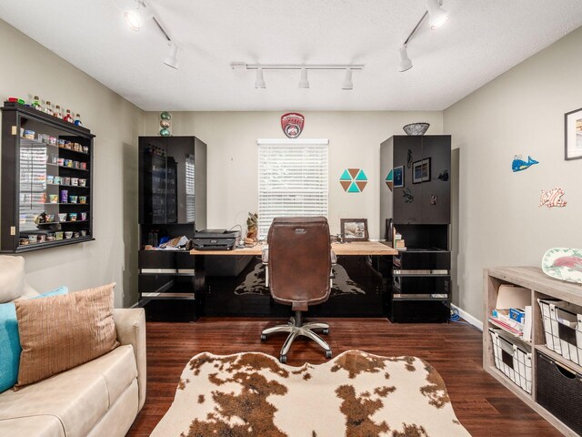 office area with dark hardwood / wood-style floors and track lighting