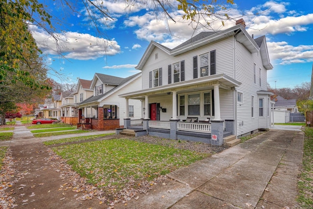 front of property featuring a porch, a garage, a front lawn, and an outdoor structure