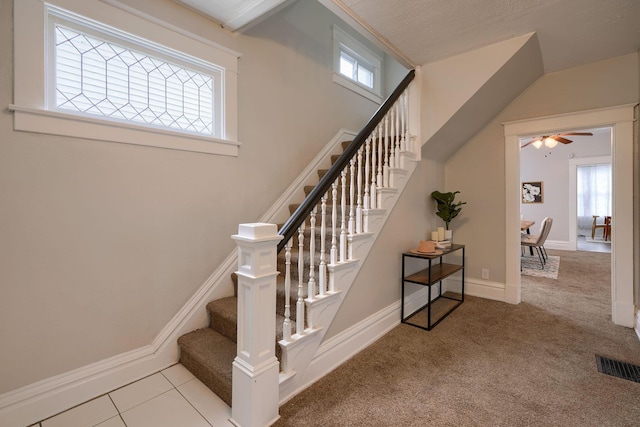 stairs with carpet flooring, ceiling fan, and a textured ceiling