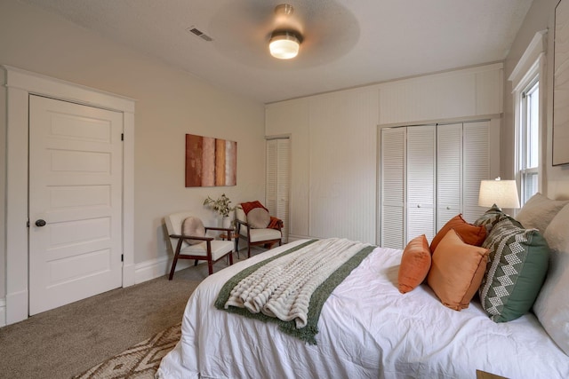 carpeted bedroom featuring ceiling fan and two closets