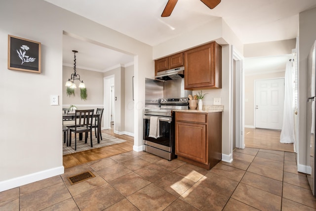 kitchen featuring dark wood-type flooring, ceiling fan with notable chandelier, stainless steel electric range oven, ornamental molding, and decorative light fixtures